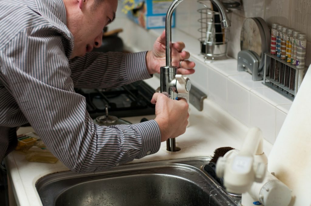 Plumber assessing a kitchen sink tap